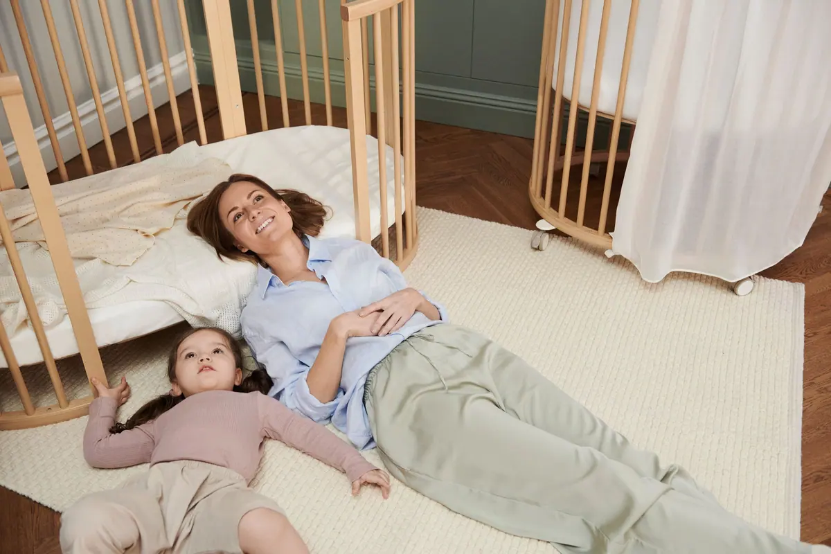คุณแม่และลูกนอนเล่นบนพรมระหว่างเตียง Sleepi Bed และ Sleepi Mini