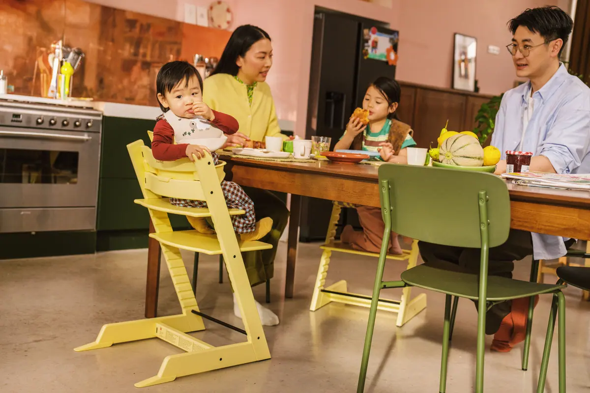 ครอบครัวกินข้าวเย็นด้วยกัน ลูกเล็กนั่งเก้าอี้ Stokke Tripp Trapp สีเหลืองพร้อม Baby Set ที่โต๊ะเดียวกับพ่อแม่